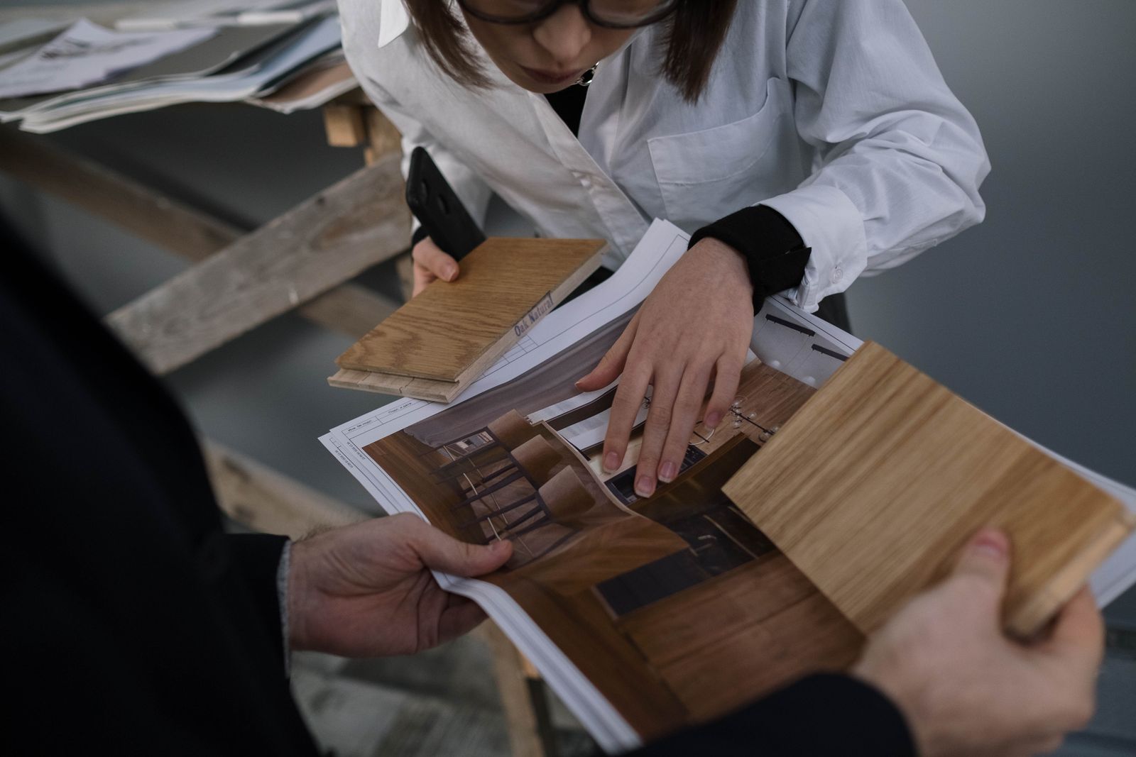 Two people reviewing kitchen drawings and material samples at a studio table